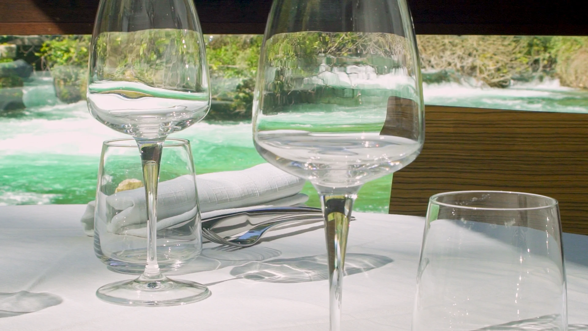 Wine glasses on a set table with turquoise Sorgue river view, Restaurant Philip